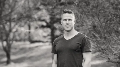 Young man standing outdoors and looking into the camera