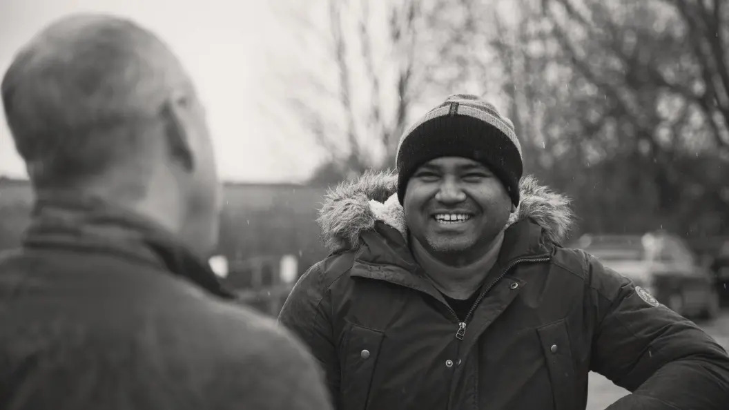 Smiling man having a conversation with a friend outside.