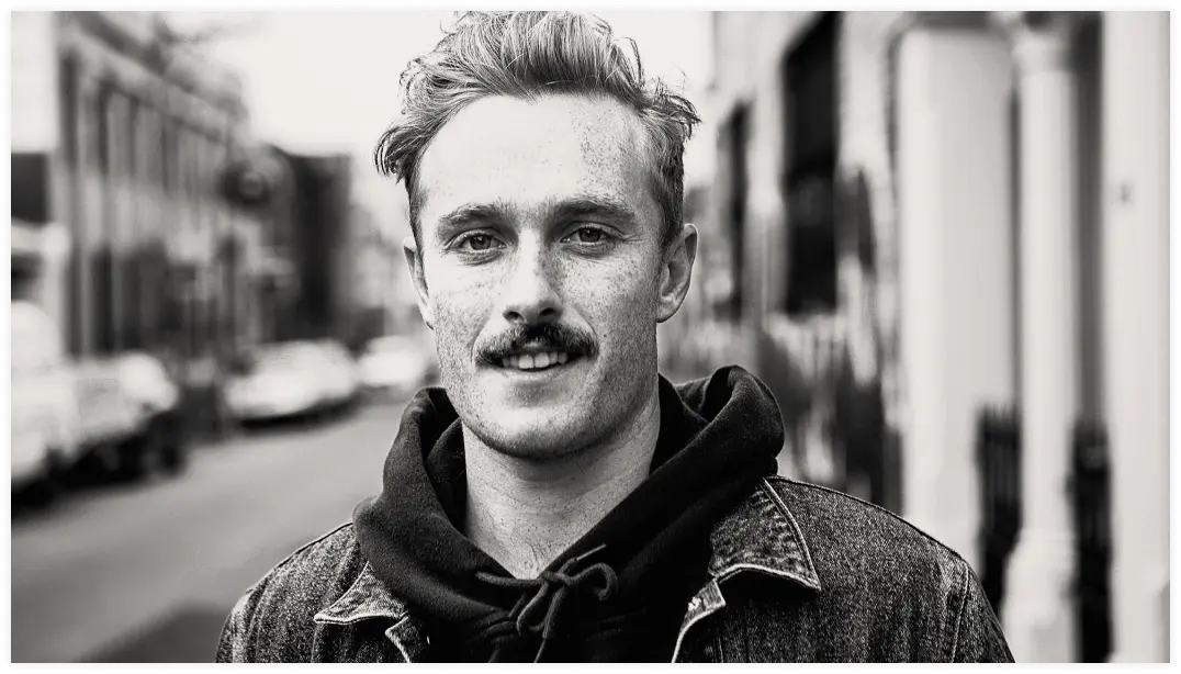 Shoulders up portrait of younger male standing in urban street.