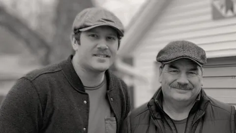 Young man and his father in front of a house